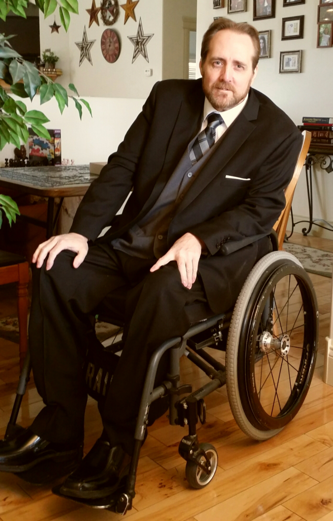 Larry in a suit and in his manual wheelchair